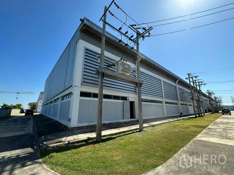 Factory for rent in Bang Bo, Samut Prakan - Exterior of a metal-clad factory building with ventilation louvers and power lines in an industrial estate.