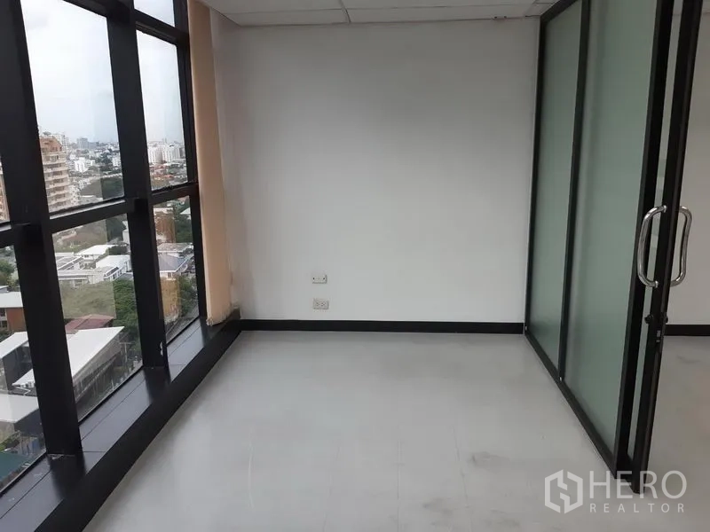 Office Space for rent in Watthana, Bangkok - Corner workspace with tall windows and a glass door, featuring urban views.