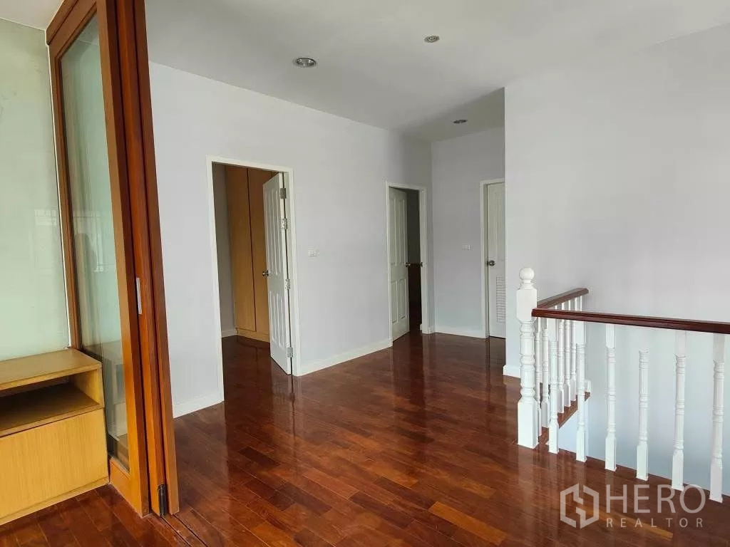 Detached House for rent or sale in Mueang Nonthaburi, Nonthaburi - Upstairs landing with glossy wooden flooring and white balustrade.