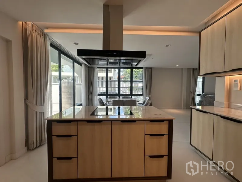 联排别墅 出租在Watthana, Bangkok - 灶台中岛面向客餐厅，落地大窗与窗帘