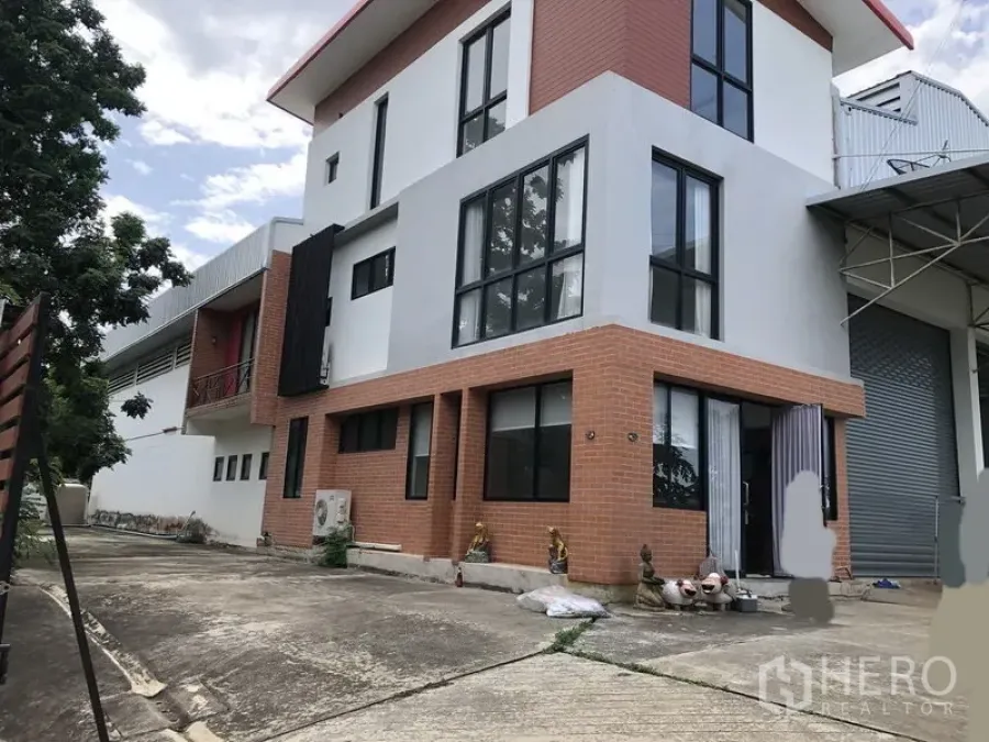 工厂 出租或出售在Lat Lum Kaeo, Pathum Thani - 厂房侧视，大片落地窗与砖立面，旁有卷闸门。