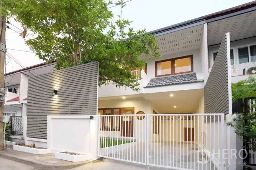Townhouse for rent in Khlong Toei, Bangkok - Modern two-storey townhouse exterior with gated carport, tree and warm lighting in Phra Khanong.