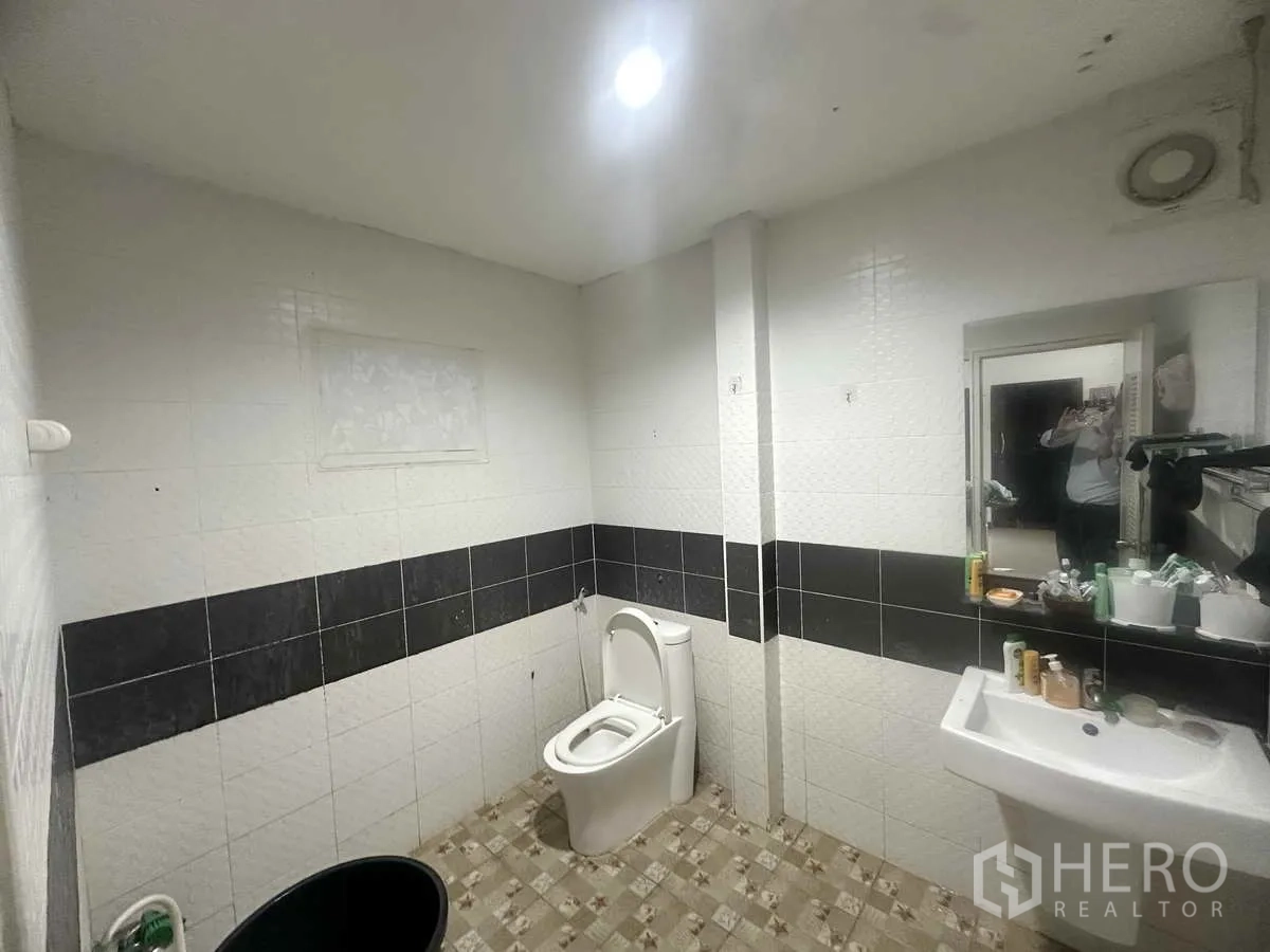 Detached House for sale in Pathum Thani - Tiled bathroom with toilet, sink, mirror and ventilation fan.