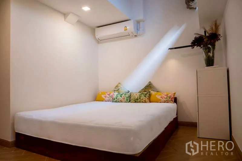 Townhouse for rent in Khlong Toei, Bangkok - Cozy bedroom with air conditioner, double bed and cabinet with flowers.
