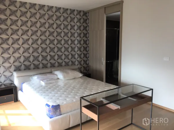 Condominium for rent in Pathum Wan, Bangkok - Master bedroom with geometric accent wall, king bed and sliding door to ensuite.