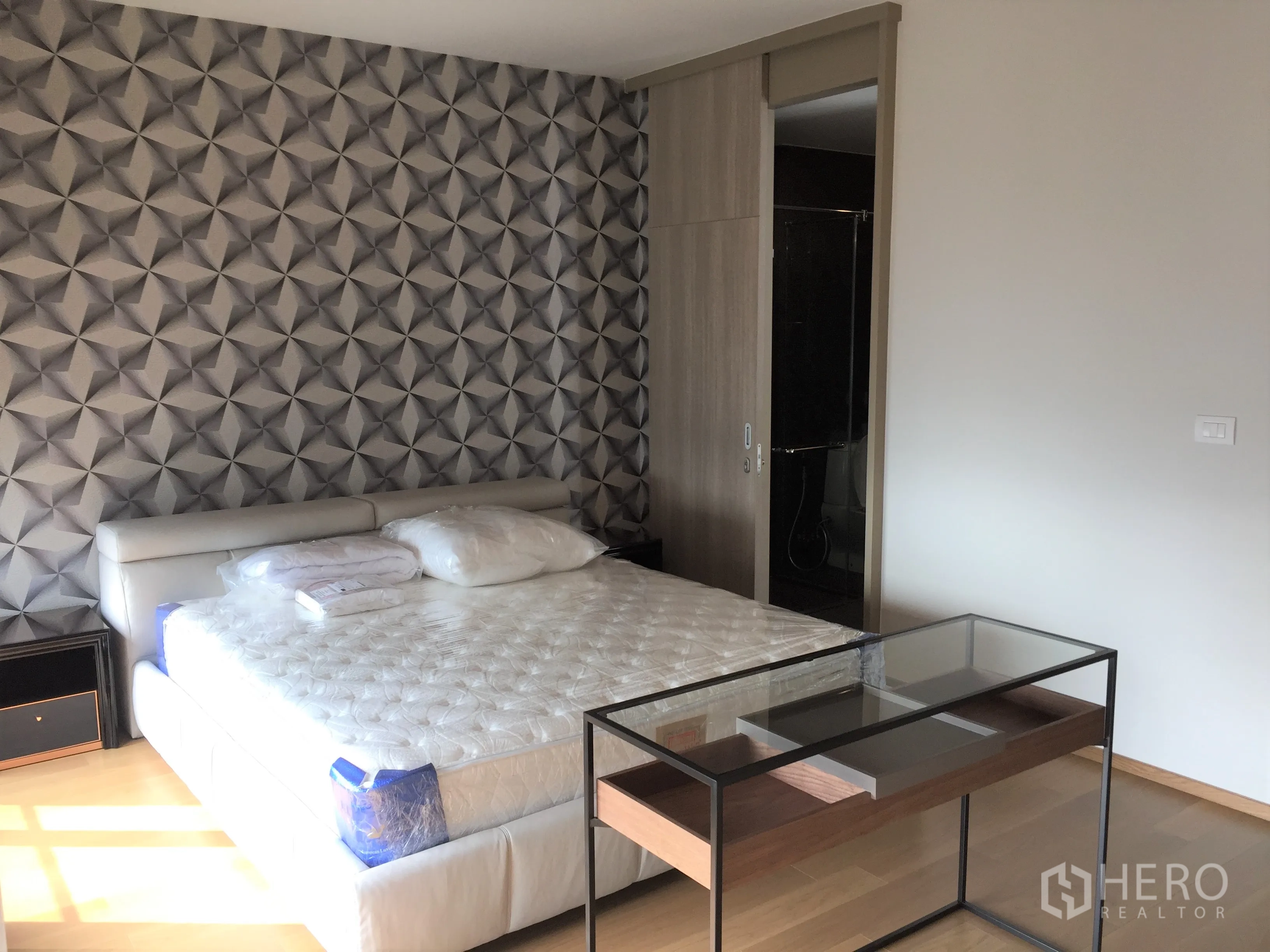 Condominium for rent in Pathum Wan, Bangkok - Master bedroom with geometric accent wall, king bed and sliding door to ensuite.