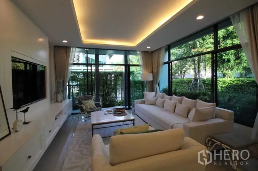 Detached House for rent in Prawet, Bangkok - Living room corner framed by floor-to-ceiling windows with garden views.