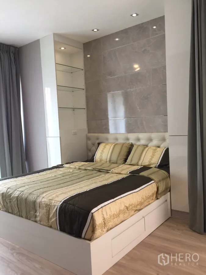 Condominium for rent or sale in Bangkok - Bright bedroom with tufted headboard, marble accent wall and built-in shelving.