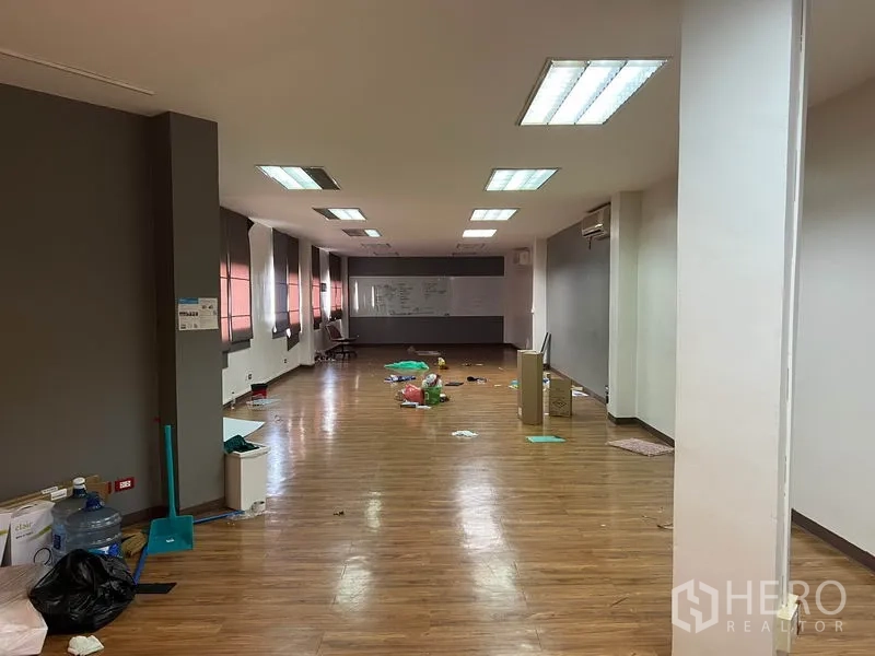 Office Space for rent in Khlong Toei, Bangkok - Open-plan office with wood floors, fluorescent ceiling lights, long windows with blinds and a whiteboard at the far end.