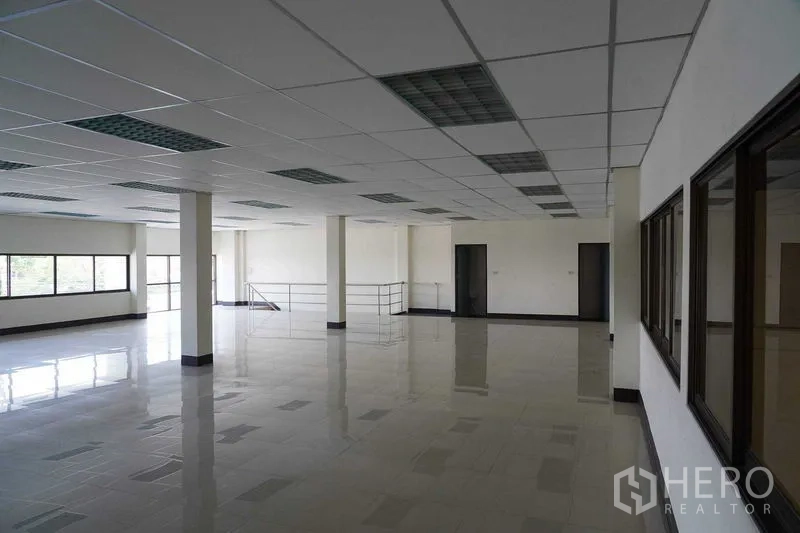 Factory for rent in Bang Sao Thong, Samut Prakan - Open‑plan office floor with tiled flooring, drop ceiling and large windows in an industrial building.