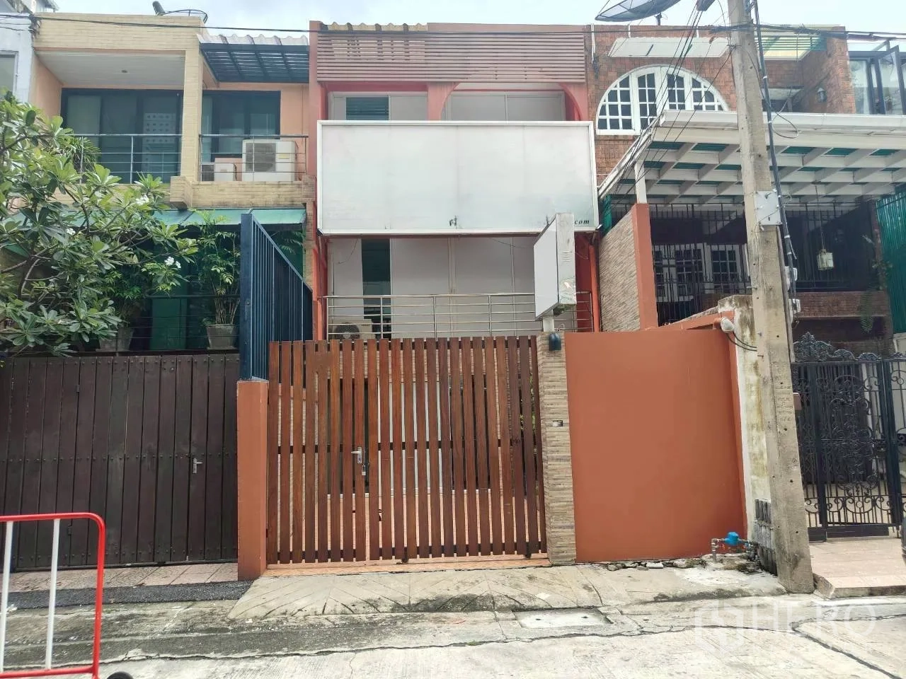 โฮมออฟฟิศ for rent in Watthana, Bangkok - หน้าบ้านทาวน์โฮมสามชั้นพร้อมรั้วไม้ระแนงและระเบียง