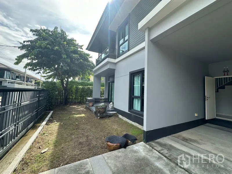 Detached House for rent in Lam Luk Ka, Pathum Thani - Side yard with small lawn, perimeter fence and covered porch.