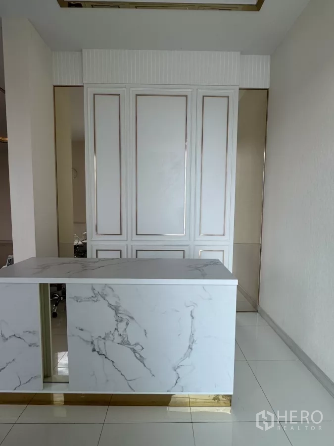 Factory for sale in Lam Luk Ka, Pathum Thani - Reception area featuring a white marble counter, paneled wall and gold trim details.