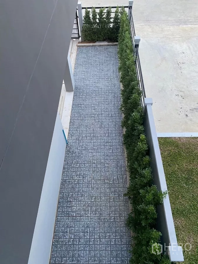 Townhouse for rent in Bang Phli, Samut Prakan - Aerial view of front driveway with patterned paving and hedge along a metal fence.