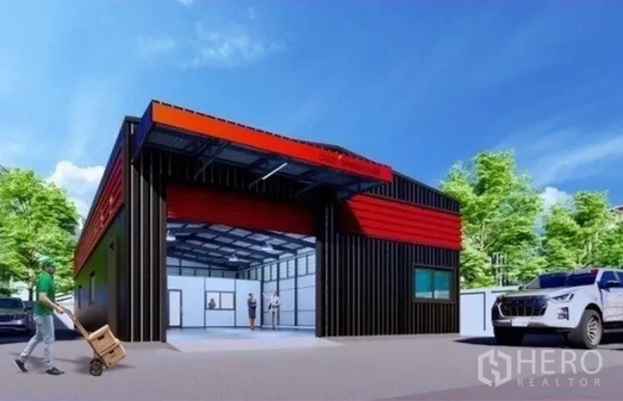 Warehouse for rent or sale in Lat Phrao, Bangkok - Modern red-and-black warehouse exterior with wide roller shutter, canopy, driveway and parking in a leafy setting.