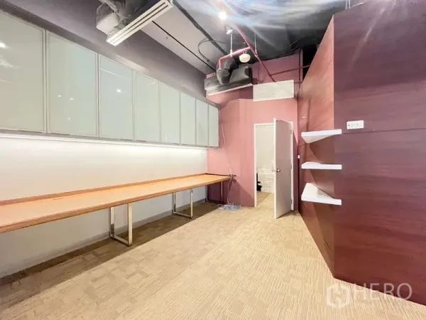 Office Space for rent in Watthana, Bangkok - Private room featuring a long wooden workbench, frosted overhead cabinets, wall shelves and a utility door.