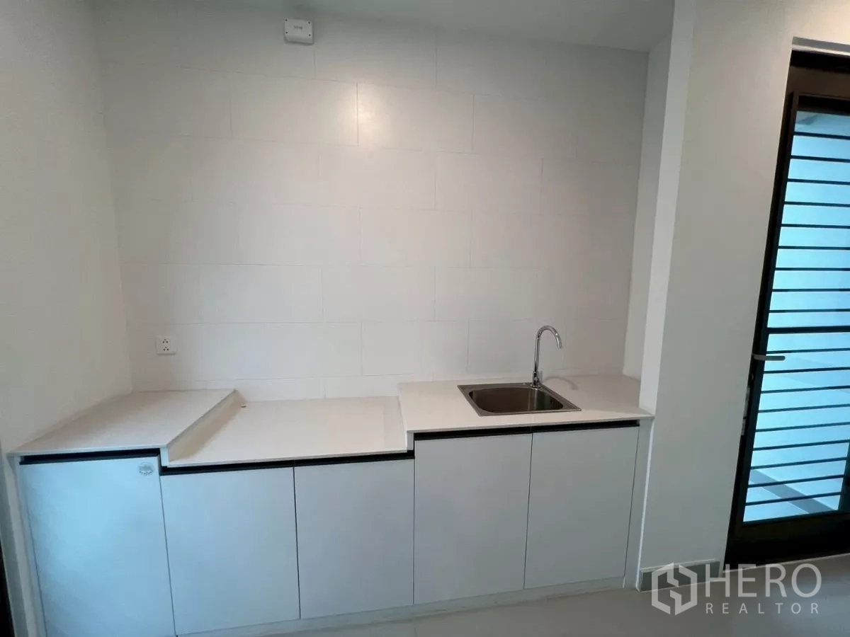 Detached House for rent in Samut Prakan - Separate Thai kitchen with durable counters, sink, and door to the yard.