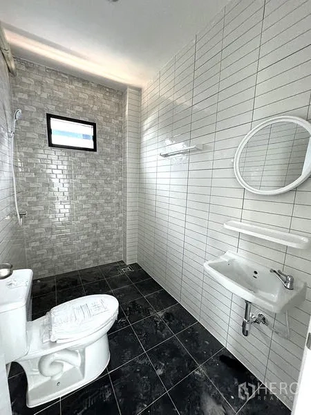 Warehouse for rent in Khlong Luang, Pathum Thani - Modern bathroom with tiled shower zone, toilet and basin with mirror.
