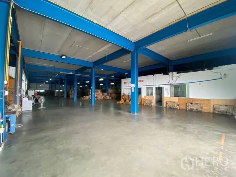 Factory for rent or sale in Lam Luk Ka, Pathum Thani - Open warehouse space showing storage zones and bright strip lighting.