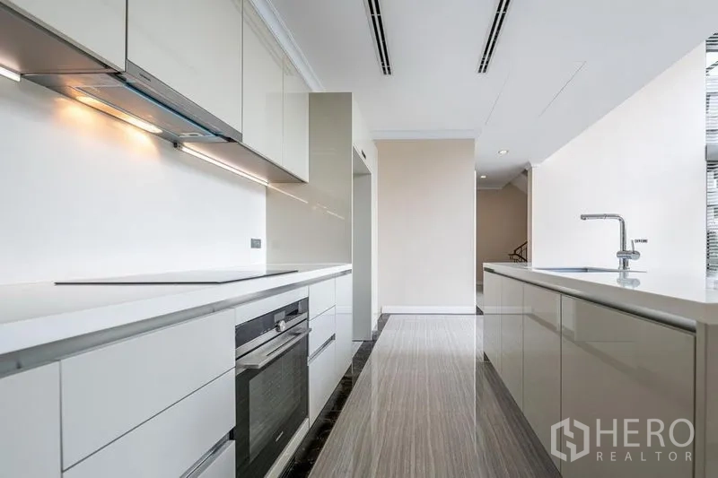 Townhouse for rent in Khlong Toei, Bangkok - Sleek white European kitchen with built-in oven, long countertops and island sink.