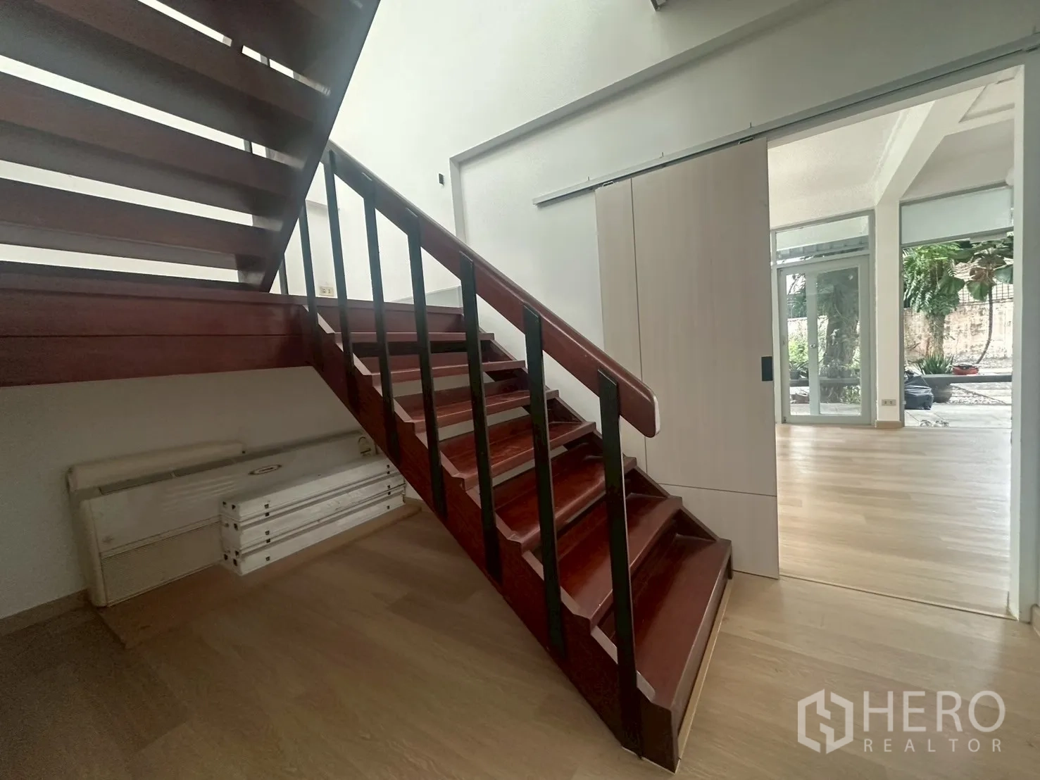 Detached House for rent in Watthana, Bangkok - Wooden staircase with dark timber steps beside a sliding door entry.