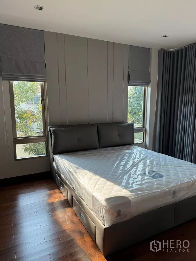Detached House for rent in Bang Phli, Samut Prakan - Bedroom with large upholstered bed, wood flooring and twin windows