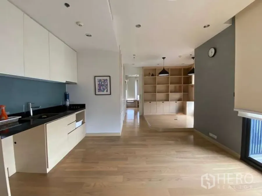 Condominium for rent or sale in Chatuchak, Bangkok - Galley kitchen with pale cabinetry leading to living area and custom shelving.