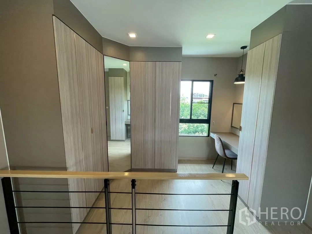Townhouse for rent in Suan Luang, Bangkok - Upstairs landing with built-in wardrobes, full-height mirror and study desk by the window.