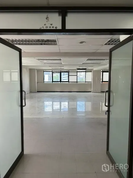 办公空间 出租在Din Daeng, Bangkok - 双扇玻璃门通向明亮的开放式办公室，瓷砖地面与采光窗。