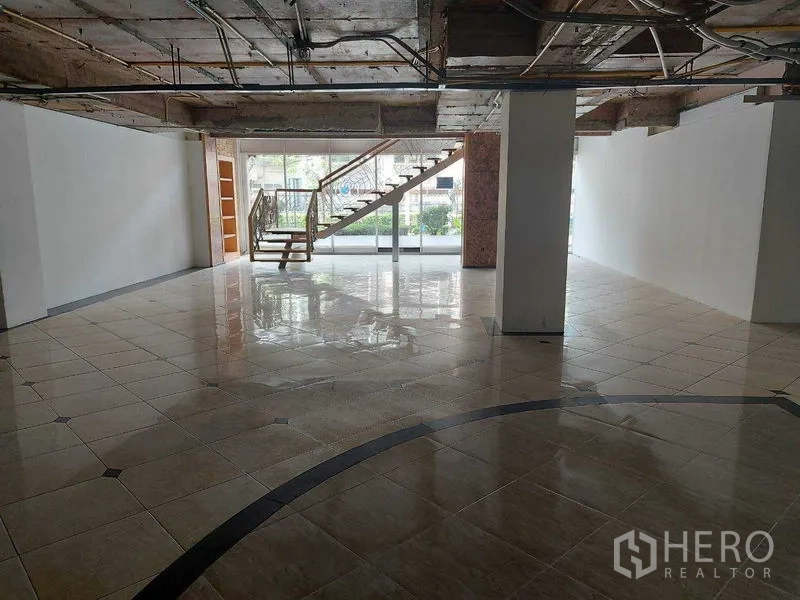 Retail Space for rent in Pathum Wan, Bangkok - Open-plan ground floor retail area with glossy tiled flooring, glass frontage and a staircase to an upper level.