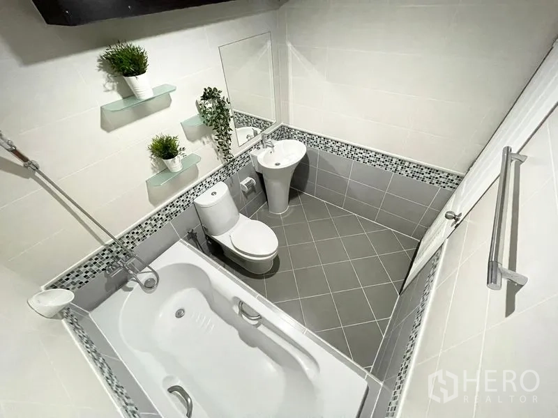 Condominium for rent in Khlong Toei, Bangkok - Second bathroom with bathtub, shower, pedestal sink, and mosaic trim.