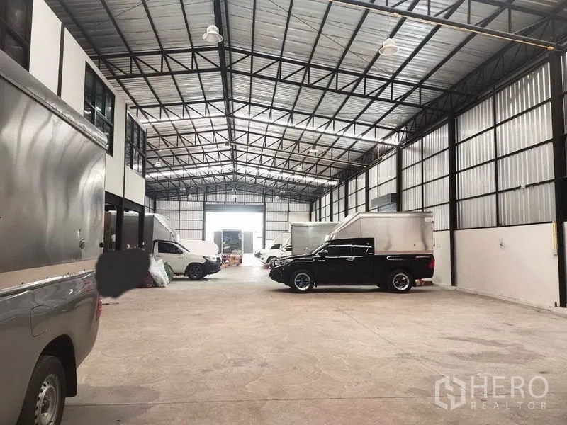 Warehouse for rent in Bang Khen, Bangkok - Warehouse in operation with pickup trucks and vans parked inside for loading and distribution.