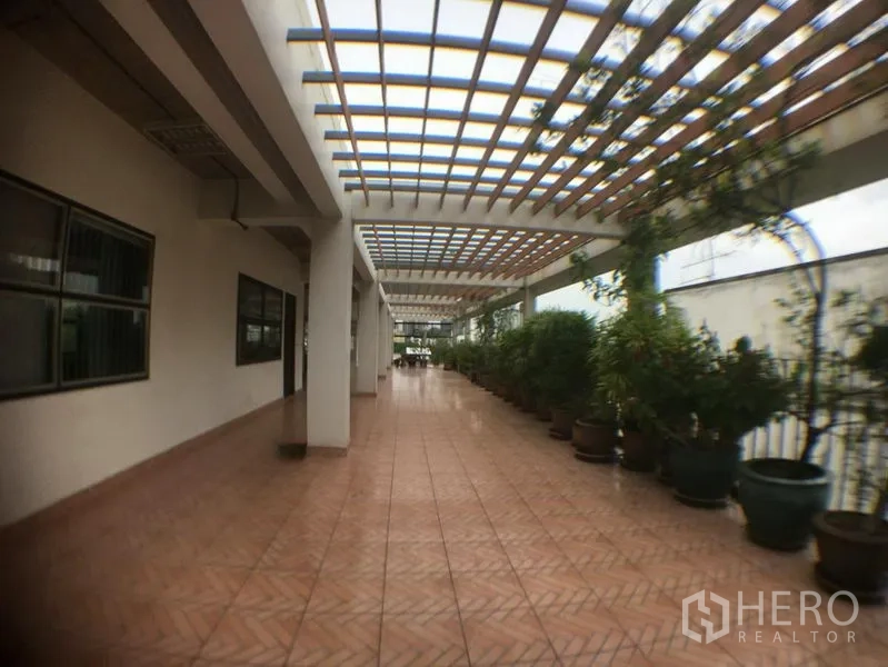 办公空间 出租在Phra Khanong, Bangkok - 覆顶屋顶步道，格栅顶与一排盆栽。