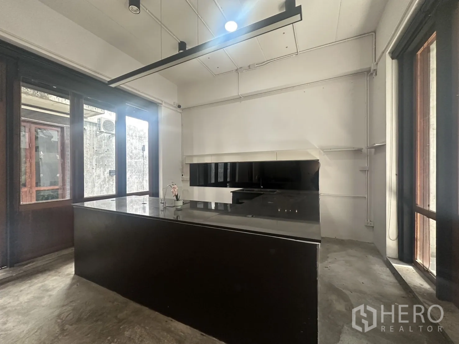 Home Office for rent in Pathum Wan, Bangkok - Open-plan room featuring a long black island counter, ideal for cafe or showroom operations.