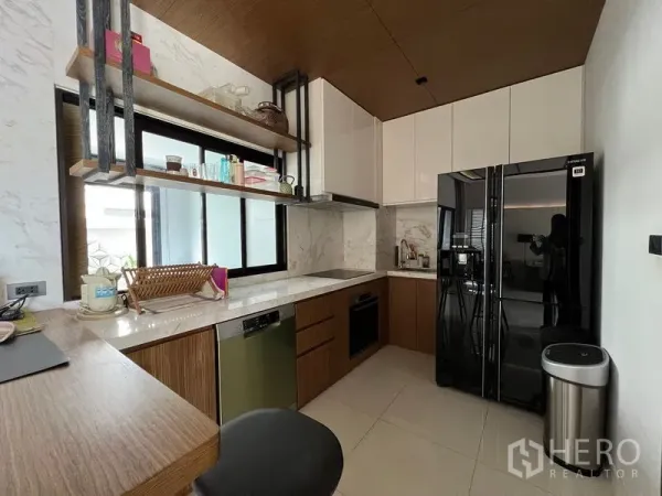 联排别墅 出租在Saphan Sung, Bangkok - 现代U形厨房，仿石材墙面，黑色冰箱与开放式置物架，窗边采光充足。