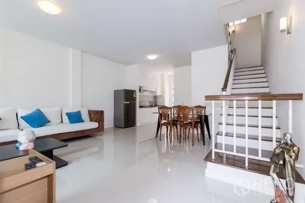 联排别墅 出租在Watthana, Bangkok - 开放式客餐厅，白色墙面、亮面地砖、小厨房与楼梯，空间通透。