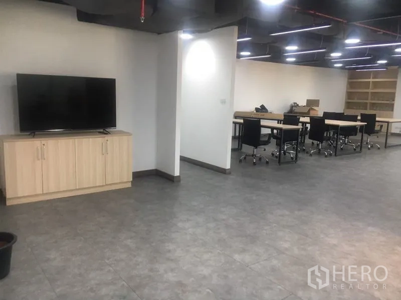 Office Space for rent in Sathon, Bangkok - Spacious office area with TV cabinet and tiled floors, opening to a large co-working zone.