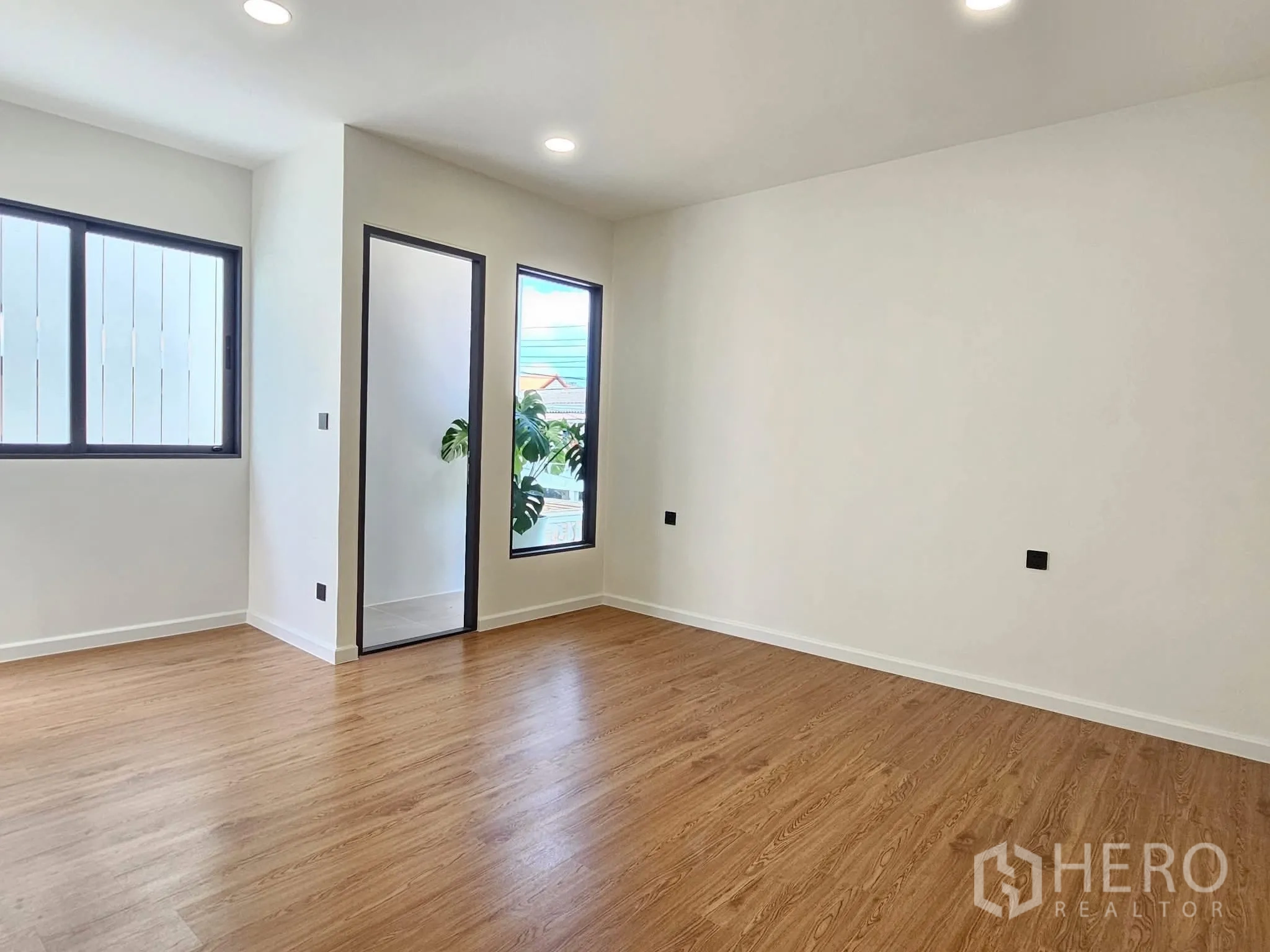 Detached House for sale in Lat Phrao, Bangkok - Spacious bedroom with large windows and a door opening to a small balcony.