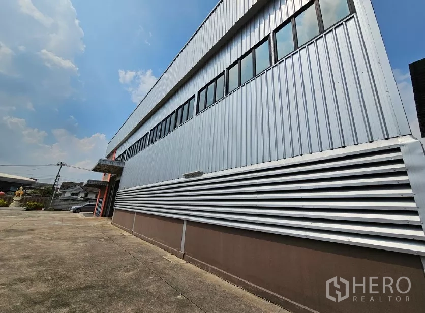 Warehouse for rent or sale in Lak Si, Bangkok - Close-up side facade of metal-clad warehouse and long driveway