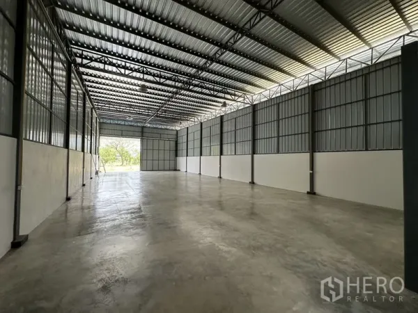 Warehouse for rent in Khlong Sam Wa, Bangkok - Open interior with skylight roof panels, clear‑span space, and a large rear shutter.