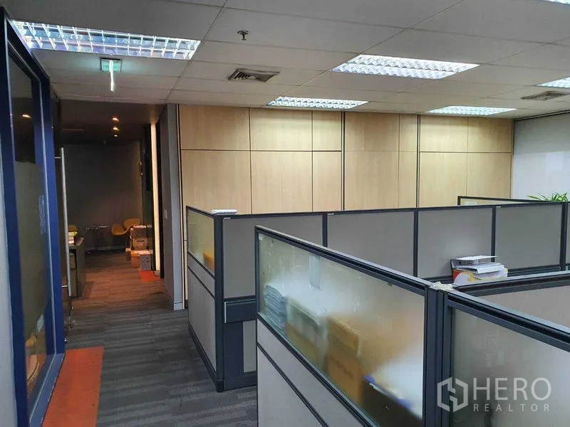 Office Space for rent in Watthana, Bangkok - Hallway leading to partitioned desks with wood-paneled wall and fluorescent ceiling lights.