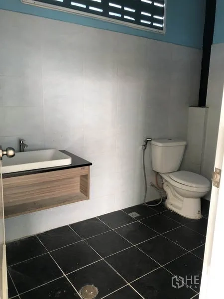 Factory for rent or sale in Bang Bua Thong, Nonthaburi - Clean tiled restroom with basin, countertop, and toilet inside the factory.