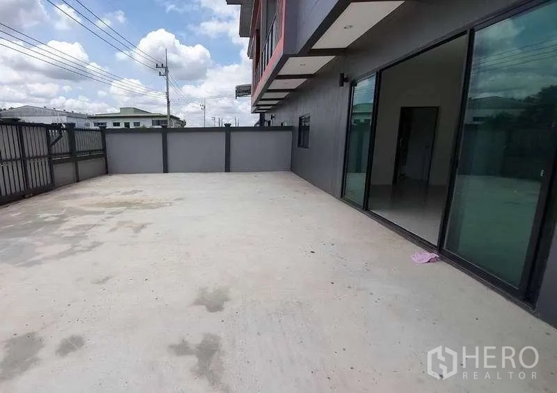 Warehouse for rent in Pathum Thani - Wide concrete yard for truck parking and loading beside the warehouse with glass-front office.