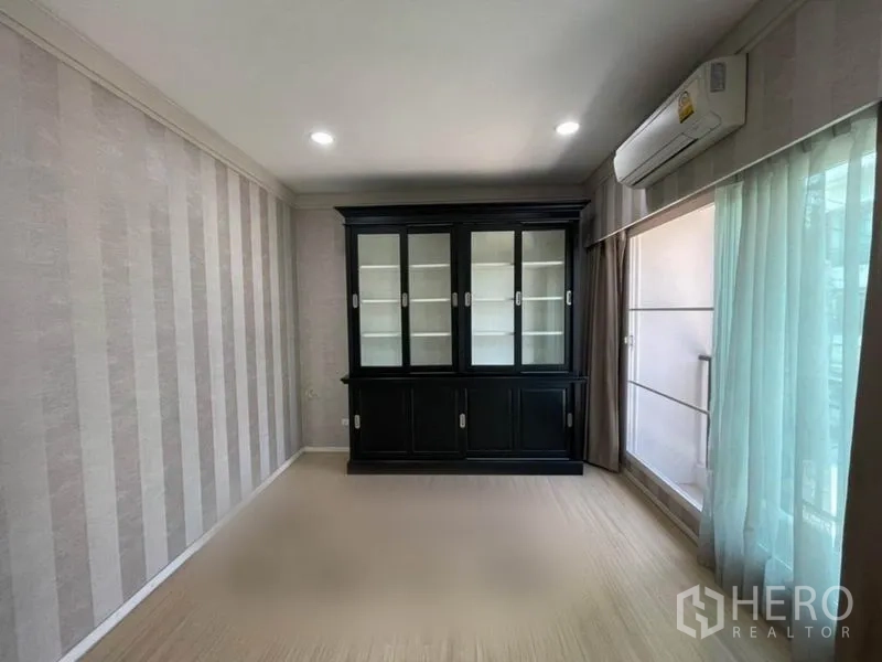 Townhouse for sale in Suan Luang, Bangkok - Bedroom or study with dark display cabinet, floor-to-ceiling curtains and air conditioner.