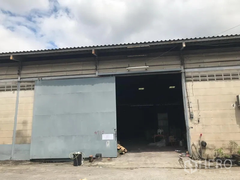 Warehouse for rent in Bang Phli, Samut Prakan - Industrial warehouse facade with large sliding metal door and driveway in Bang Phli.