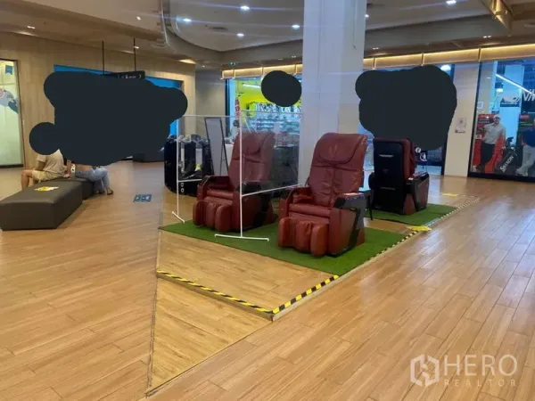 Retail Space for rent in Khlong Toei, Bangkok - Corner retail space with massage chairs on a raised platform, wood flooring and ceiling lights inside a shopping mall.