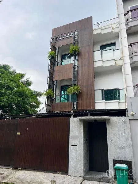 联排别墅 出租在Phaya Thai, Bangkok - 联排别墅近景，木质立面与安全滑动大门。