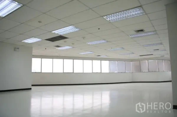 Office Space for rent in Chatuchak, Bangkok - Spacious open-plan office with grid ceiling, fluorescent lighting, and a long run of windows.
