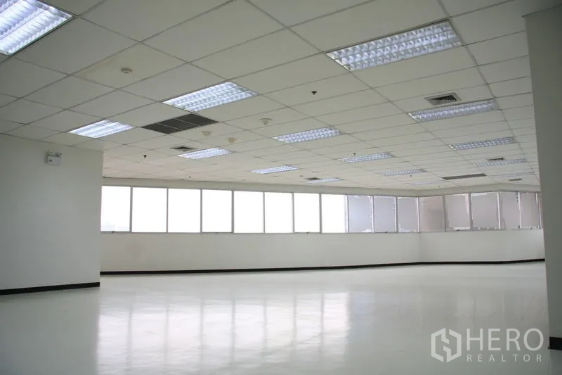 Office Space for rent in Chatuchak, Bangkok - Spacious open-plan office with grid ceiling, fluorescent lighting, and a long run of windows.