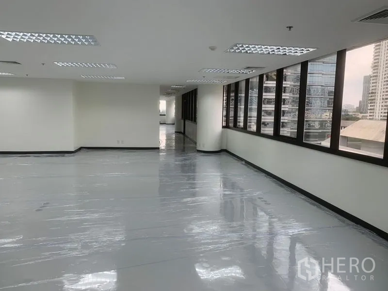 Office Space for rent in Bang Rak, Bangkok - Corner of empty office space with a long row of city‑view windows and recessed ceiling lights.